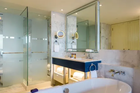 Grand Room bathroom with soaking tub, glass shower, and blue vanity at Grand Hyatt Baha Mar.