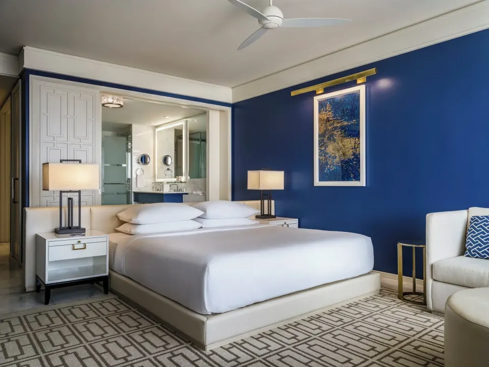 King bed in a blue-walled Grand Room at Grand Hyatt Baha Mar with seating and open bathroom view.