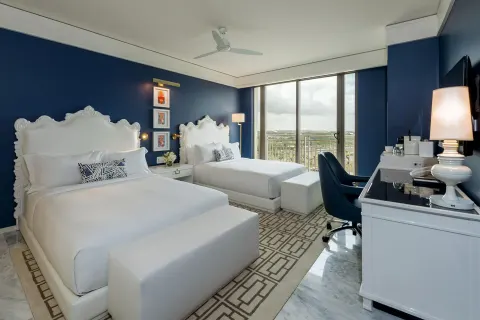Two double beds in a Grand Room at Grand Hyatt Baha Mar with balcony doors and a desk.