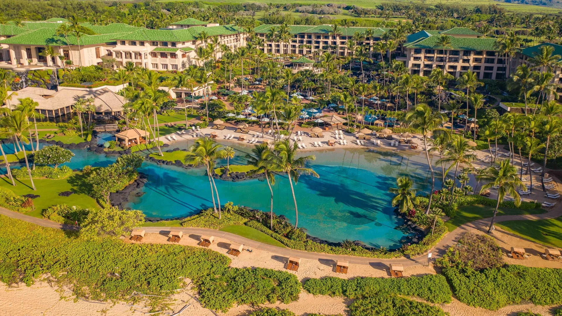 Aerial view of pools, palms and resort buildings at Grand Hyatt Kauai Resort and Spa and Spa.