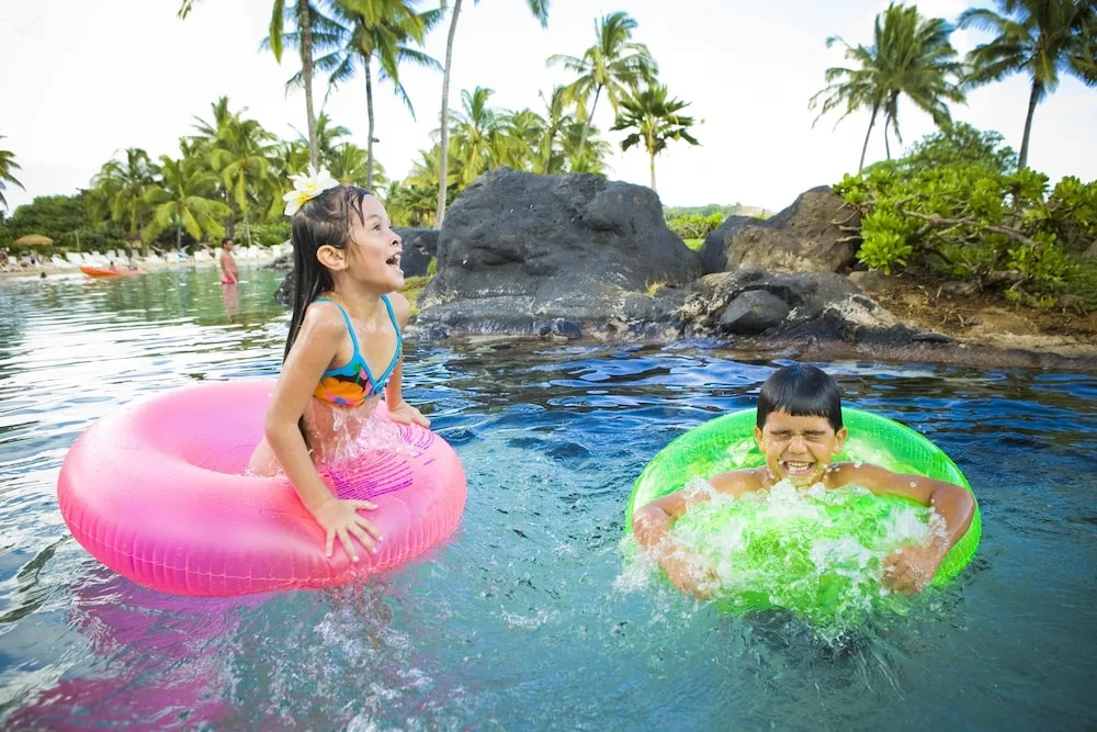 Children play on pool floats in the water at Grand Hyatt Kauai Resort and Spa and Spa.