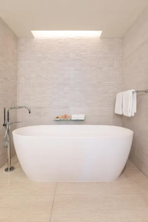 Freestanding soaking tub in a tiled bathroom at Grand Hyatt Kauai Resort and Spa and Spa.