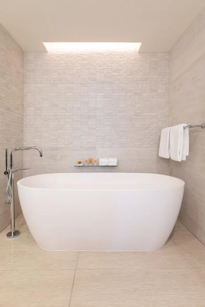 Freestanding soaking tub in a tiled bathroom at Grand Hyatt Kauai Resort and Spa and Spa.