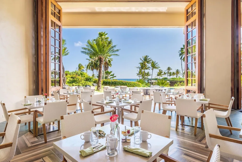 Bright dining room opening to palms and ocean at Grand Hyatt Kauai Resort and Spa and Spa.
