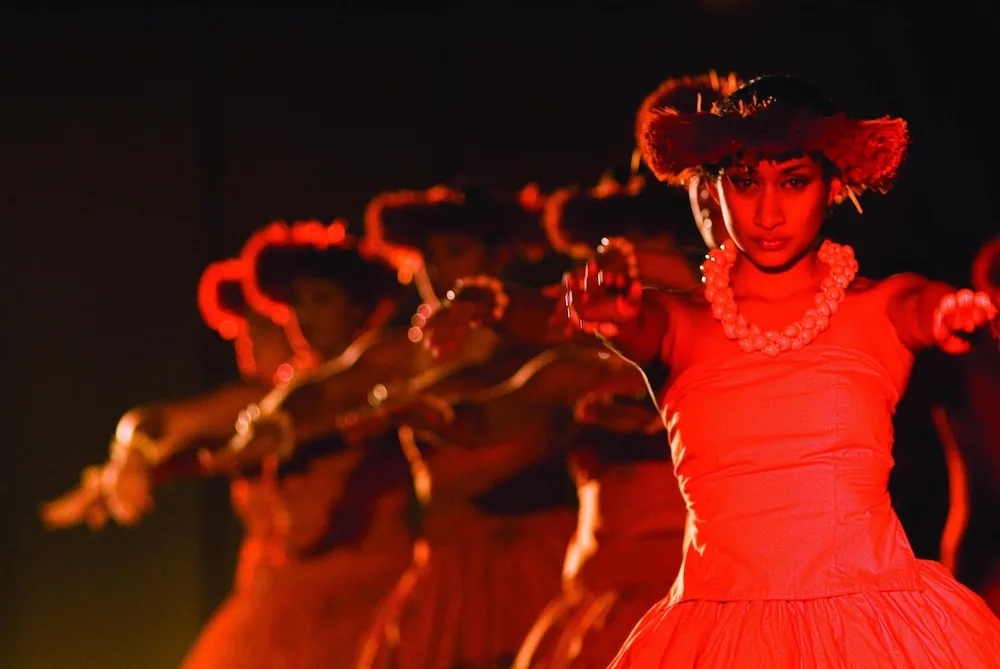 Polynesian dancers performing under red stage lighting at Grand Hyatt Kauai Resort and Spa and Spa.