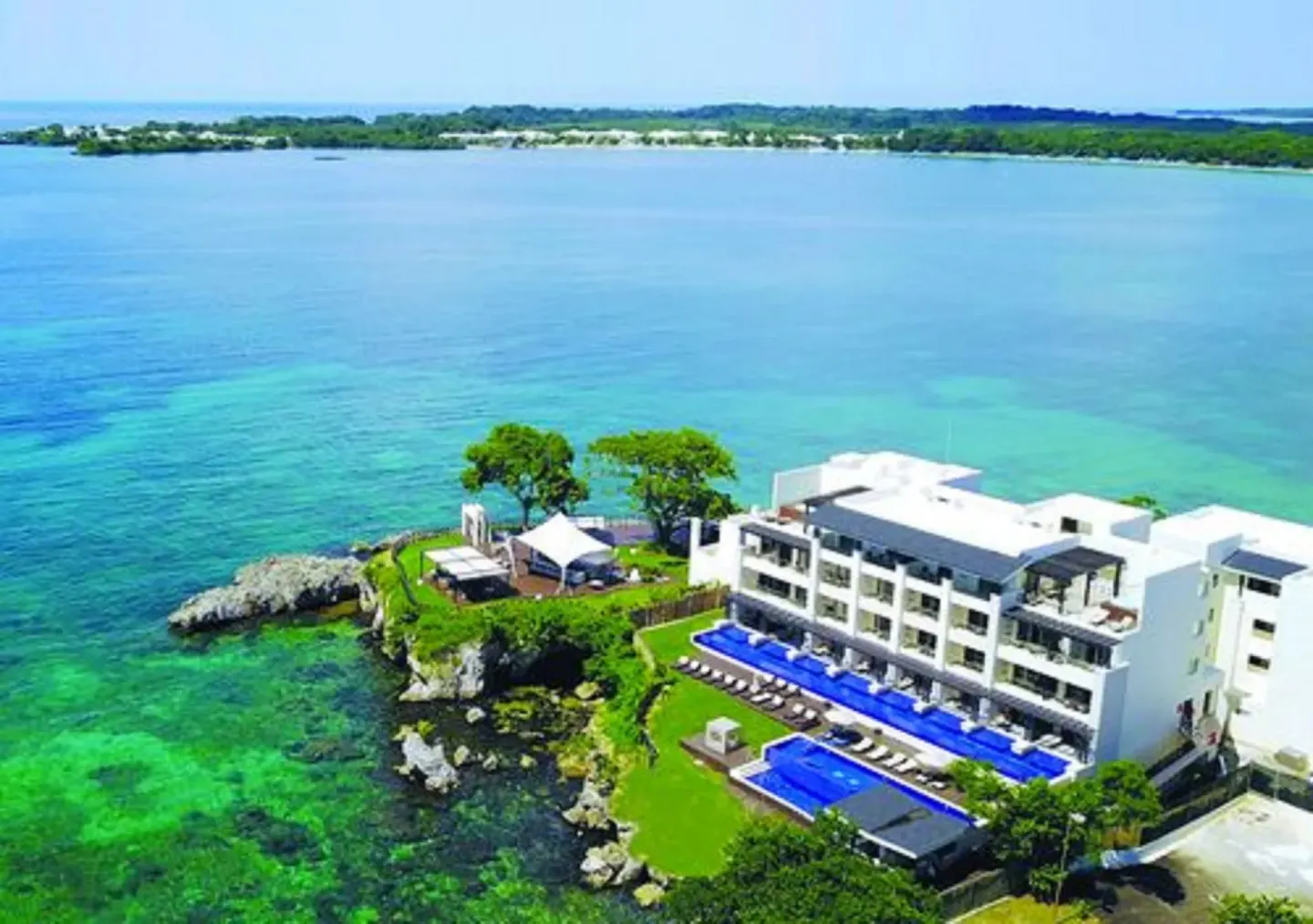 Aerial view of an oceanfront pool and white building at Grand Lido Negril Au-Naturel.