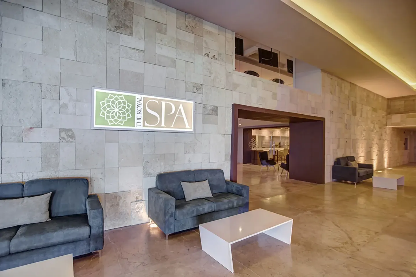 Spa reception lounge with sofas and illuminated sign at Grand Lido Negril Au-Naturel.
