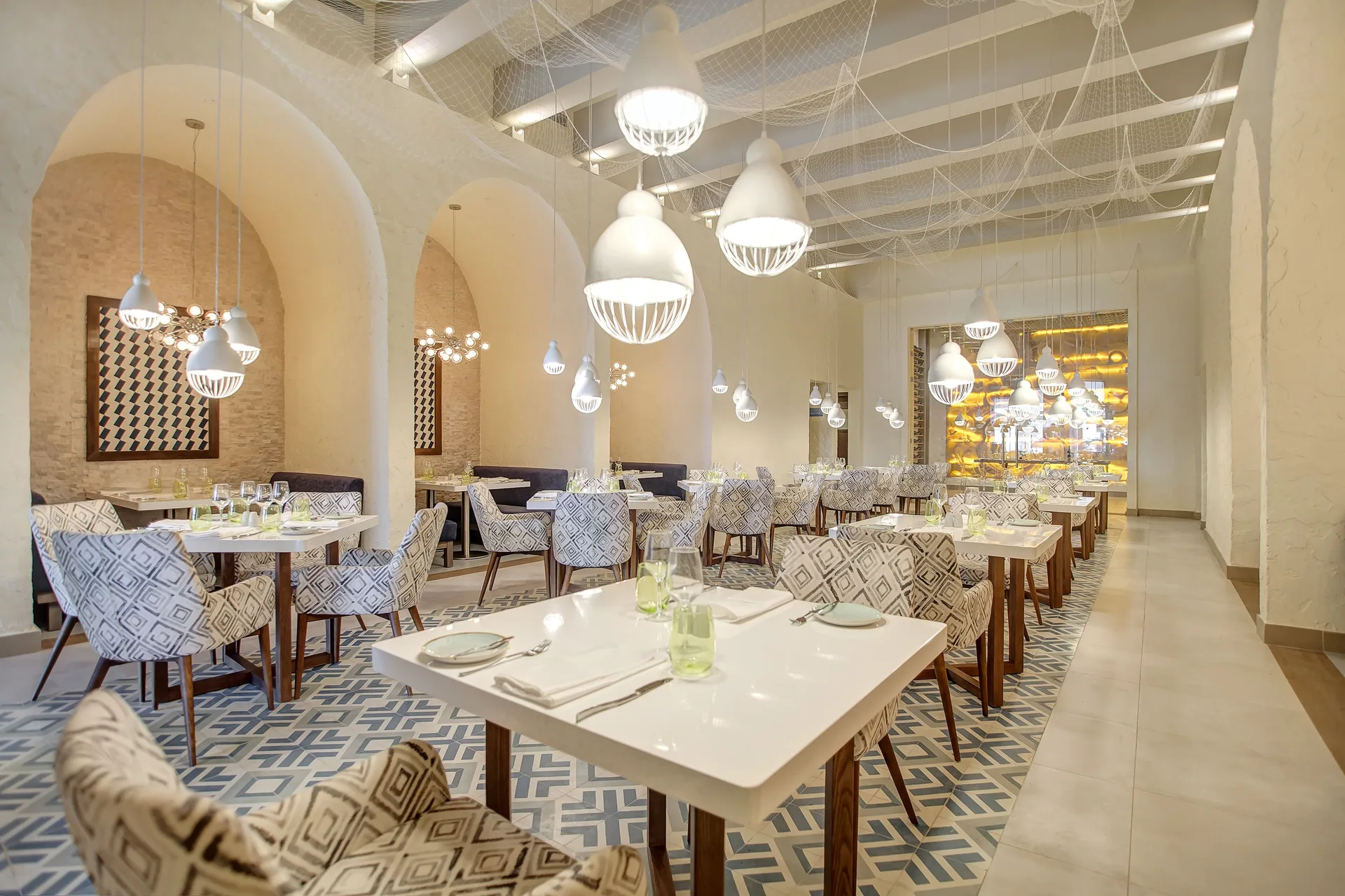 Bright dining room with patterned chairs and pendant lights at Grand Lido Negril Au-Naturel.