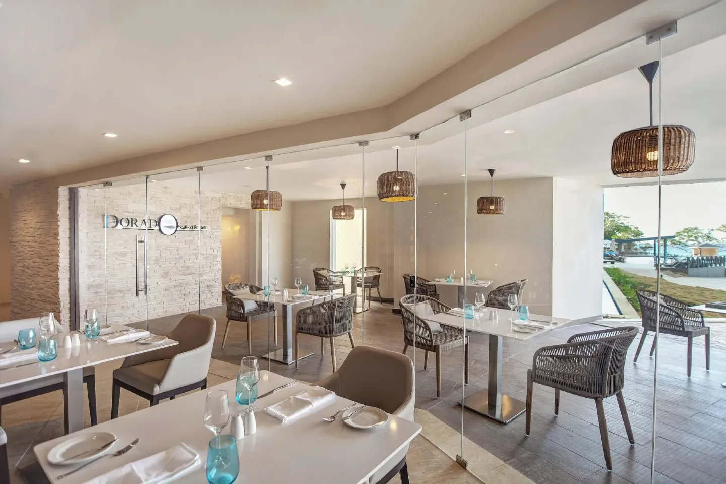 Dorado dining area with glass walls and set tables at Grand Lido Negril Au-Naturel.
