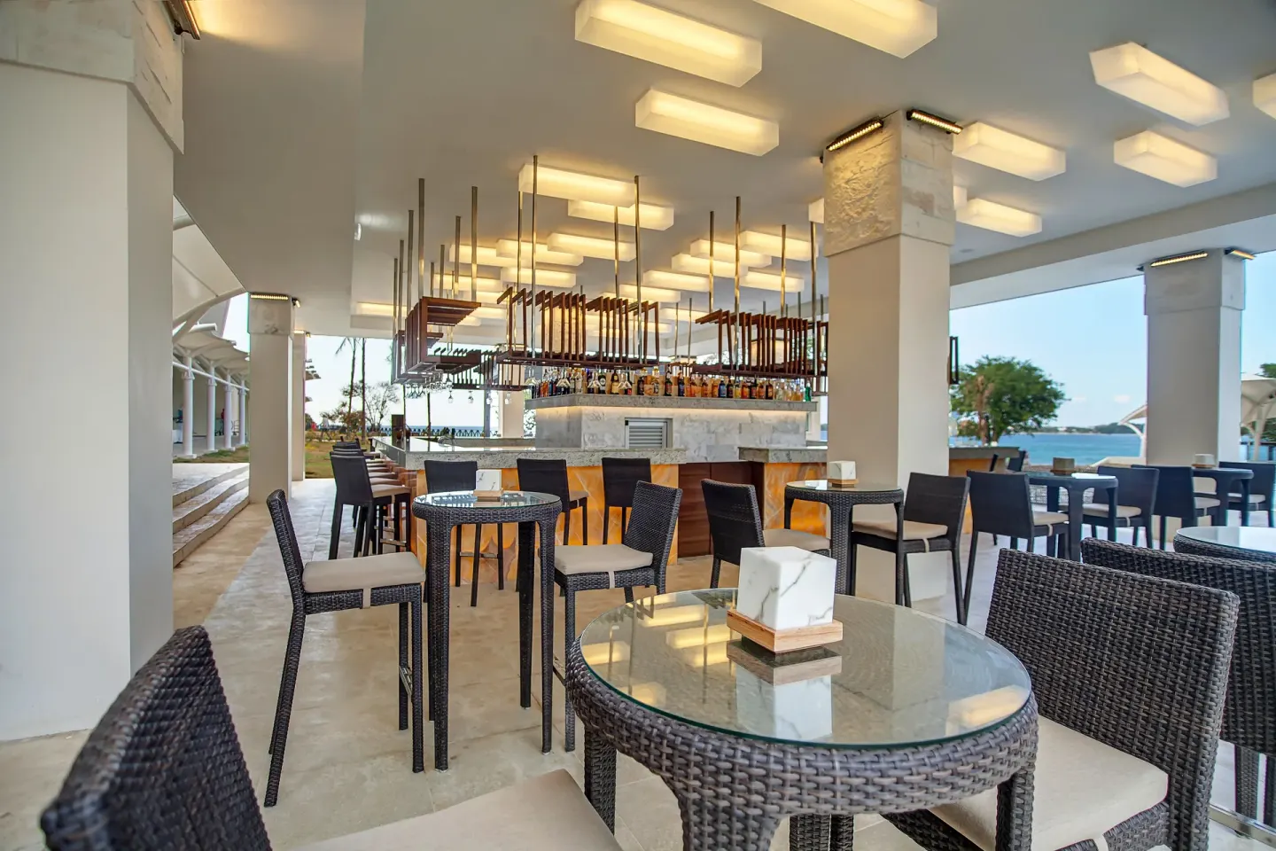 Open-air bar with wicker seating and ocean glimpses at Grand Lido Negril Au-Naturel.