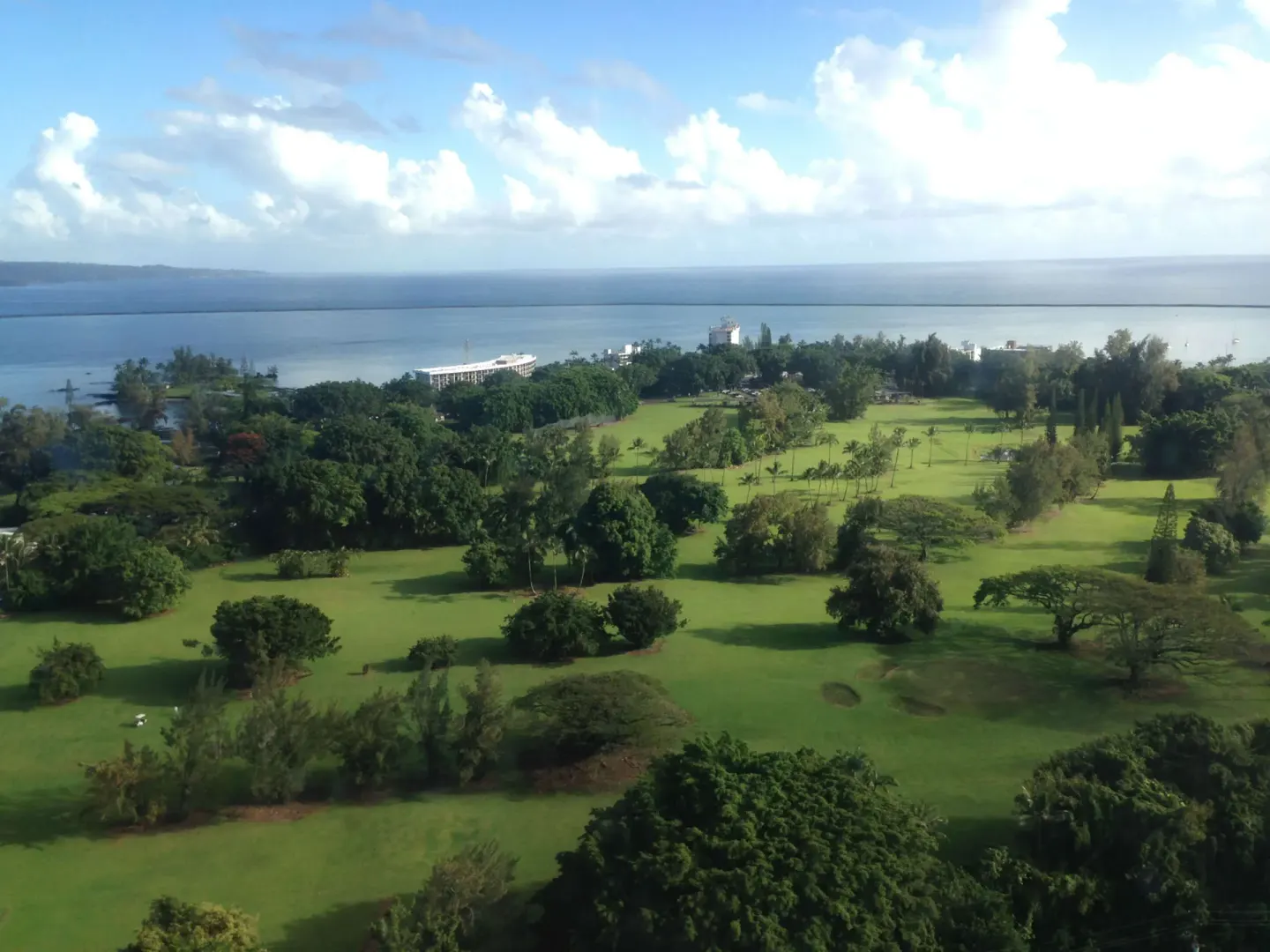 Aerial view of green grounds, trees, and Hilo Bay near Grand Naniloa Hotel Hilo.