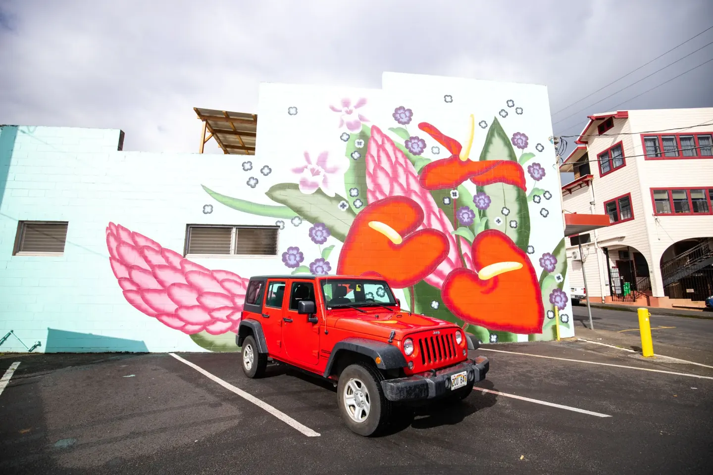 Colorful floral mural with a red vehicle near Grand Naniloa Hotel Hilo.