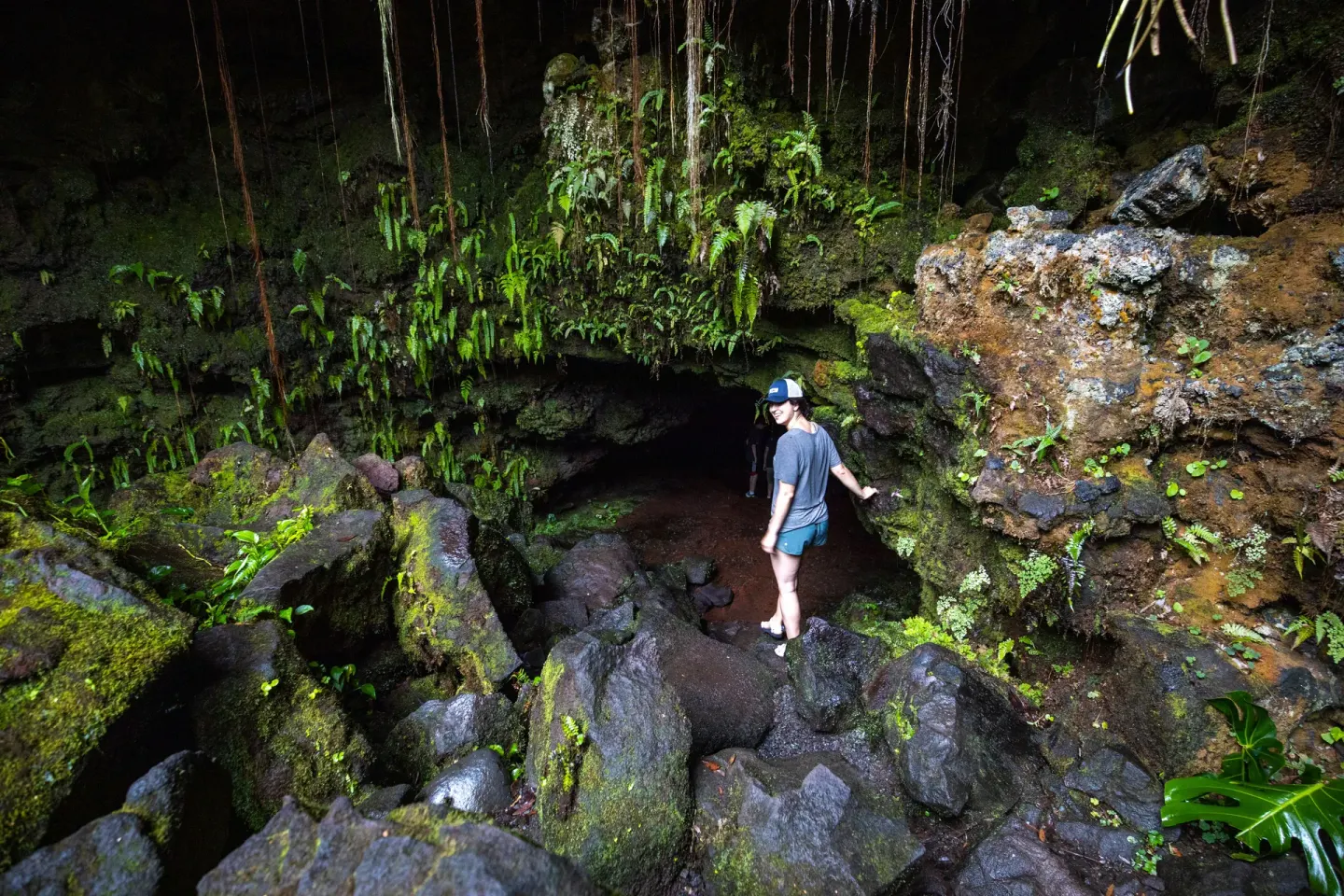 Hiker among mossy rocks, vines, and ferns near Grand Naniloa Hotel Hilo.