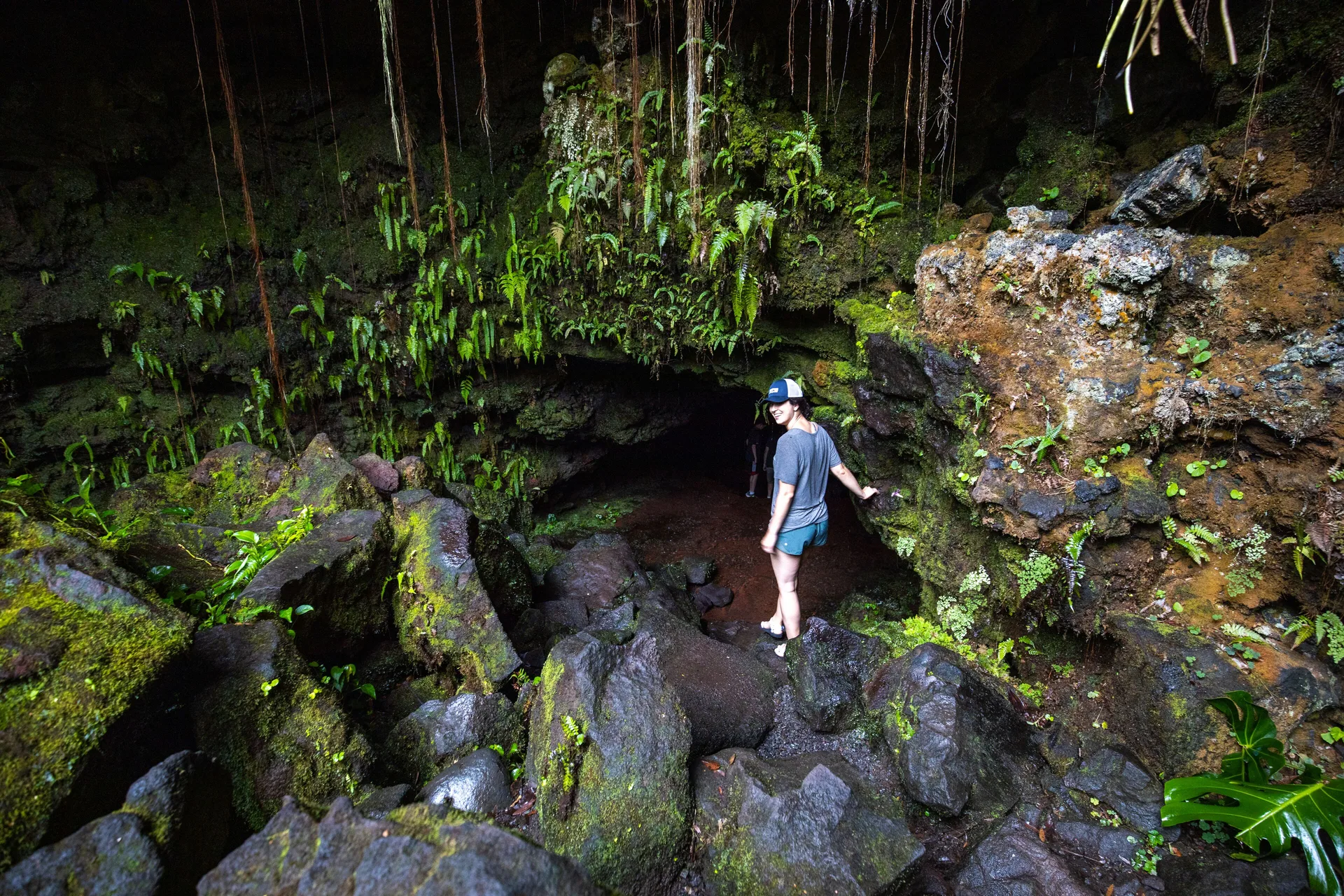 Hiker among mossy rocks, vines, and ferns near Grand Naniloa Hotel Hilo.