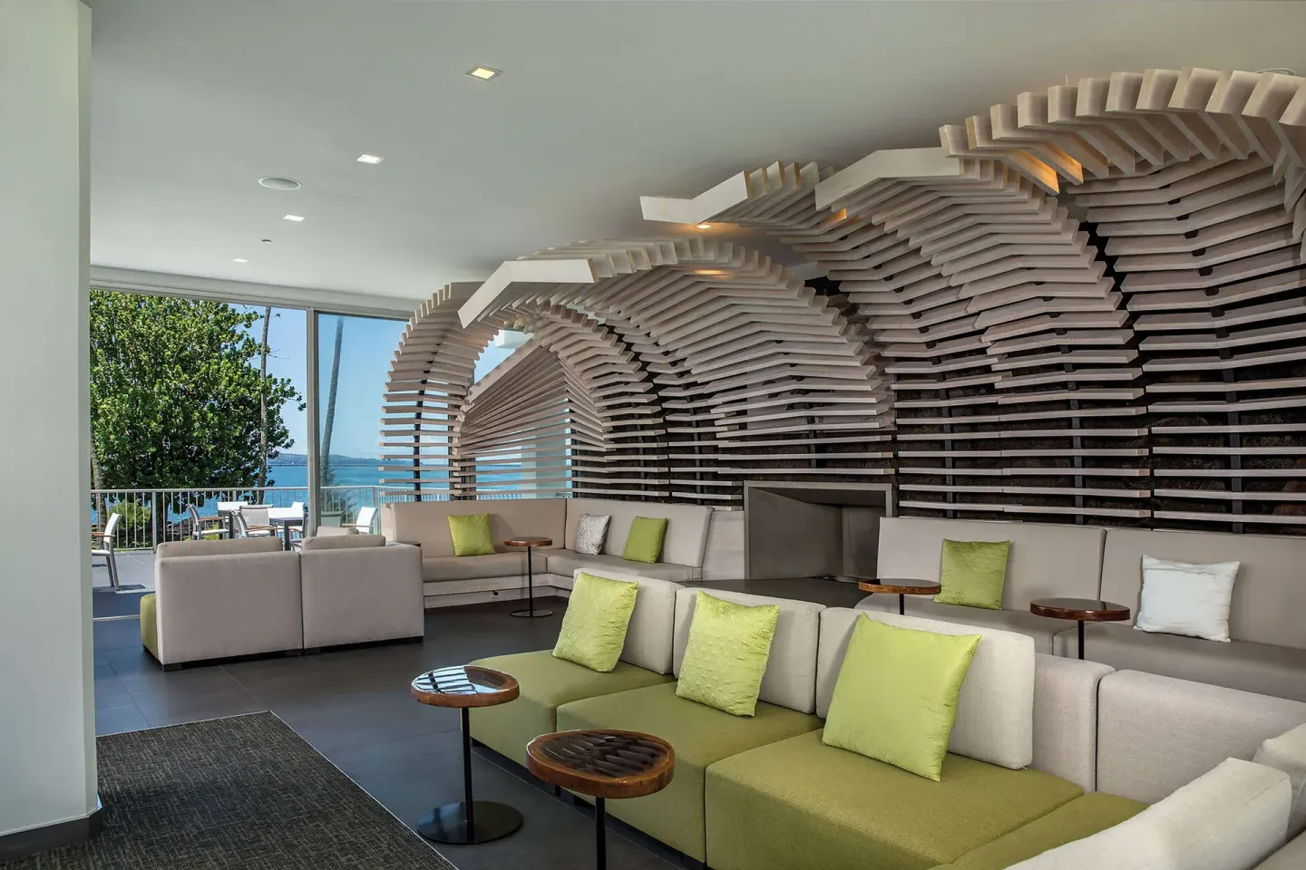 Lobby seating with sculptural wood wall and ocean-facing windows at Grand Naniloa Hotel Hilo.