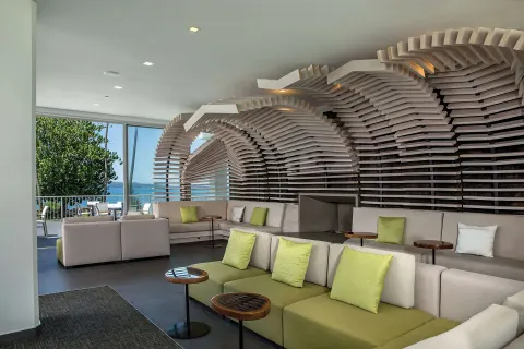 Lobby seating with sculptural wood wall and ocean-facing windows at Grand Naniloa Hotel Hilo.