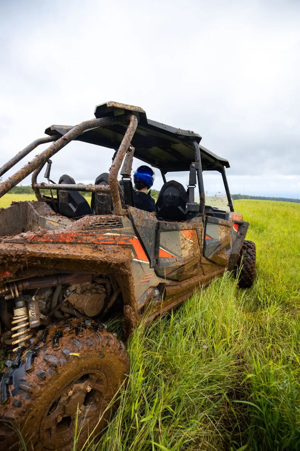 Muddy off-road vehicle in tall grass during an excursion from Grand Naniloa Hotel Hilo.