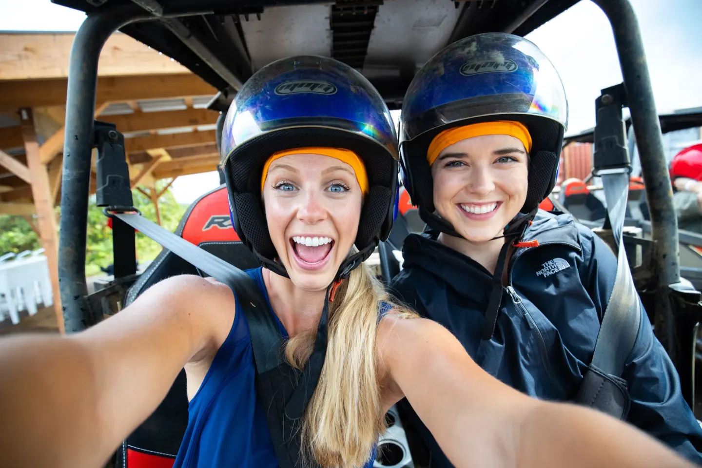 Two helmeted riders seated in an off-road vehicle at Grand Naniloa Hotel Hilo.