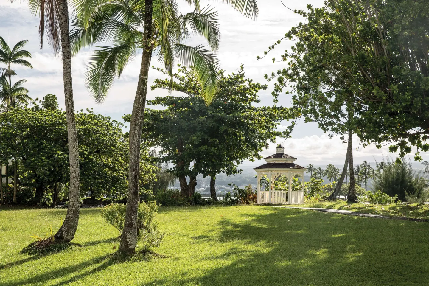 Palm lawn and white gazebo on the grounds at Grand Naniloa Hotel Hilo.