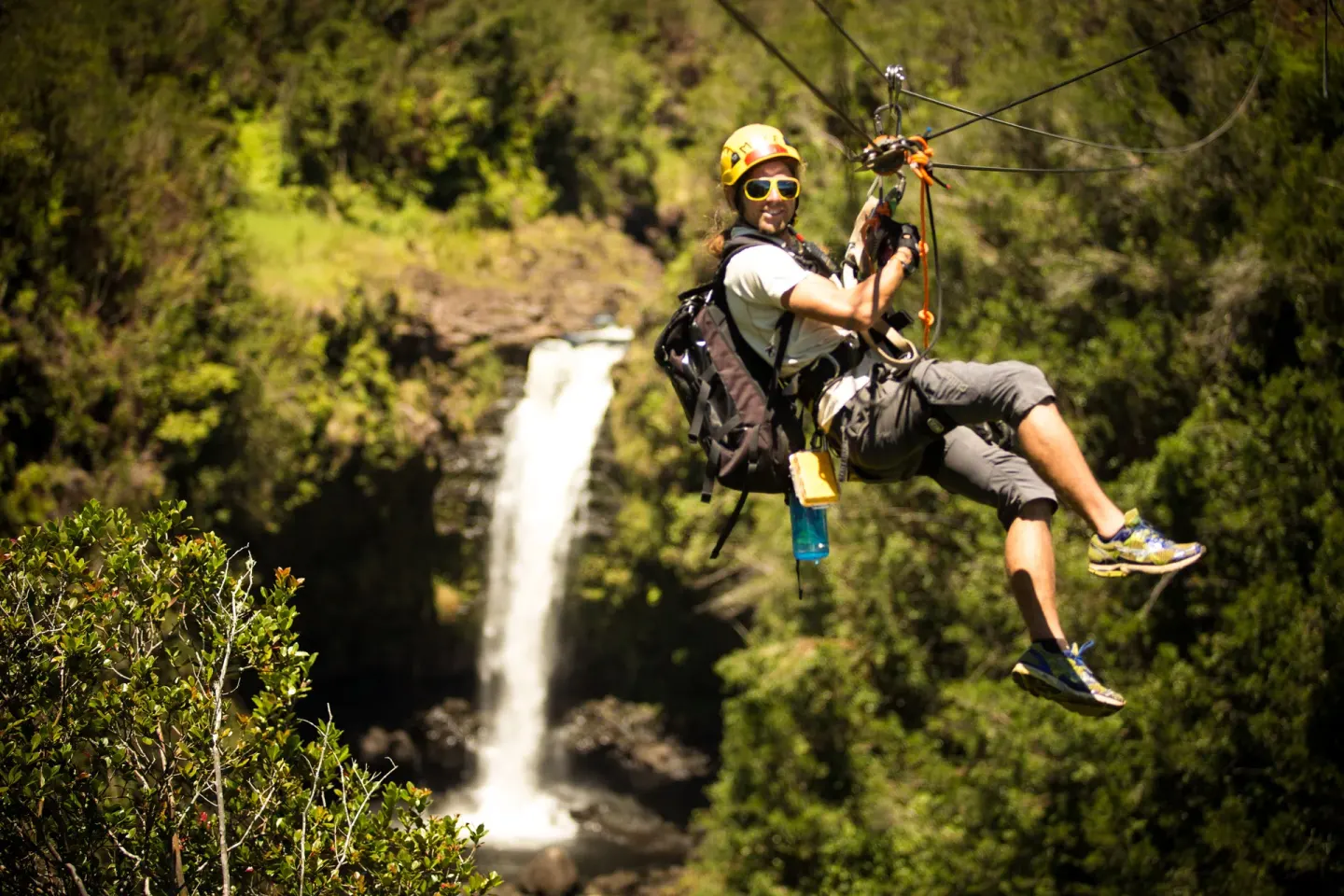 A zipline rider passes a waterfall near Grand Naniloa Hotel Hilo.