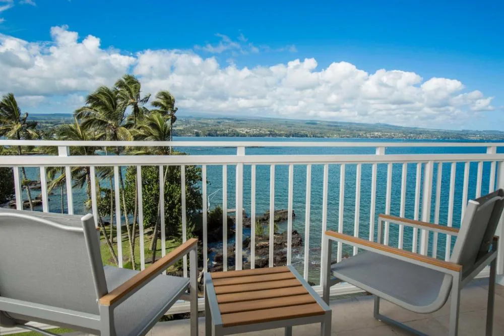 Lanai seating with ocean and palm views from an accessible king room at Grand Naniloa Hotel Hilo.