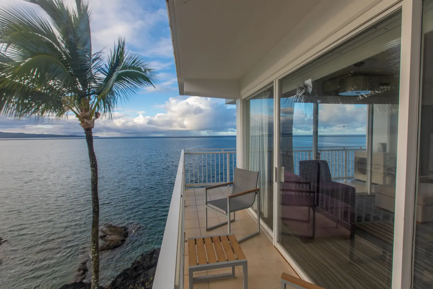 Oceanfront junior suite balcony with chairs and water view at Grand Naniloa Hotel Hilo.