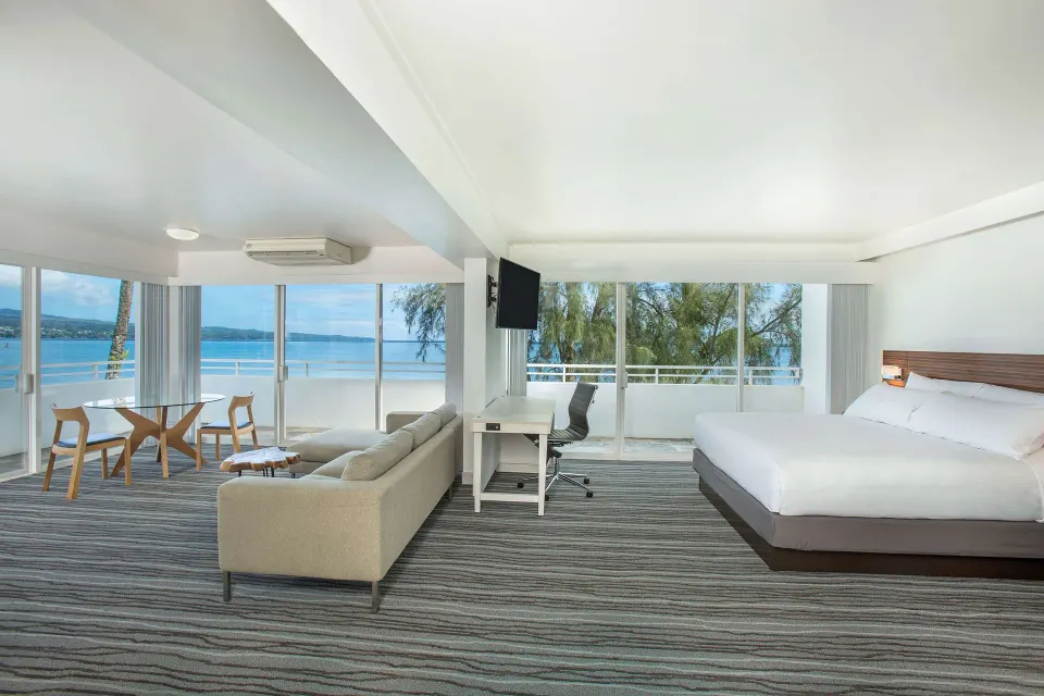 Spacious oceanfront junior suite with king bed and sitting area at Grand Naniloa Hotel Hilo.