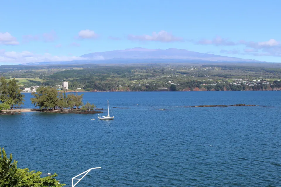 Ocean View Room outlook over Hilo Bay from Grand Naniloa Hotel Hilo with sailboat and distant mountains.