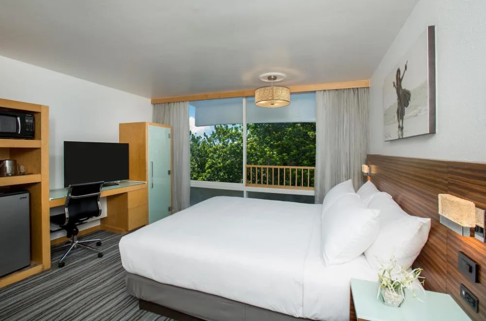 Ocean View Room with king bed, desk, TV, and large window at Grand Naniloa Hotel Hilo.