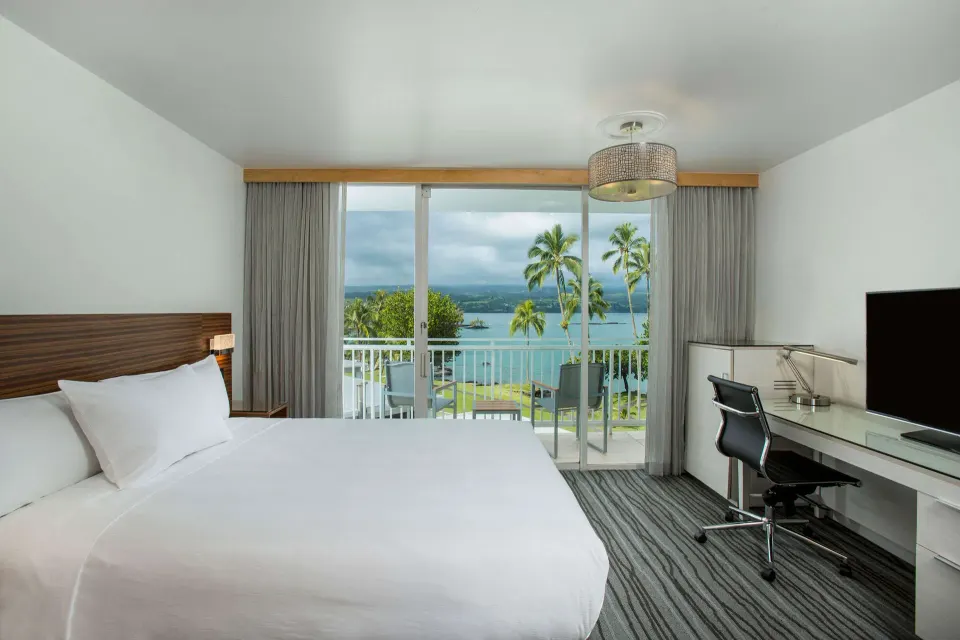 King guest room with desk, lanai, and ocean view at Grand Naniloa Hotel Hilo.
