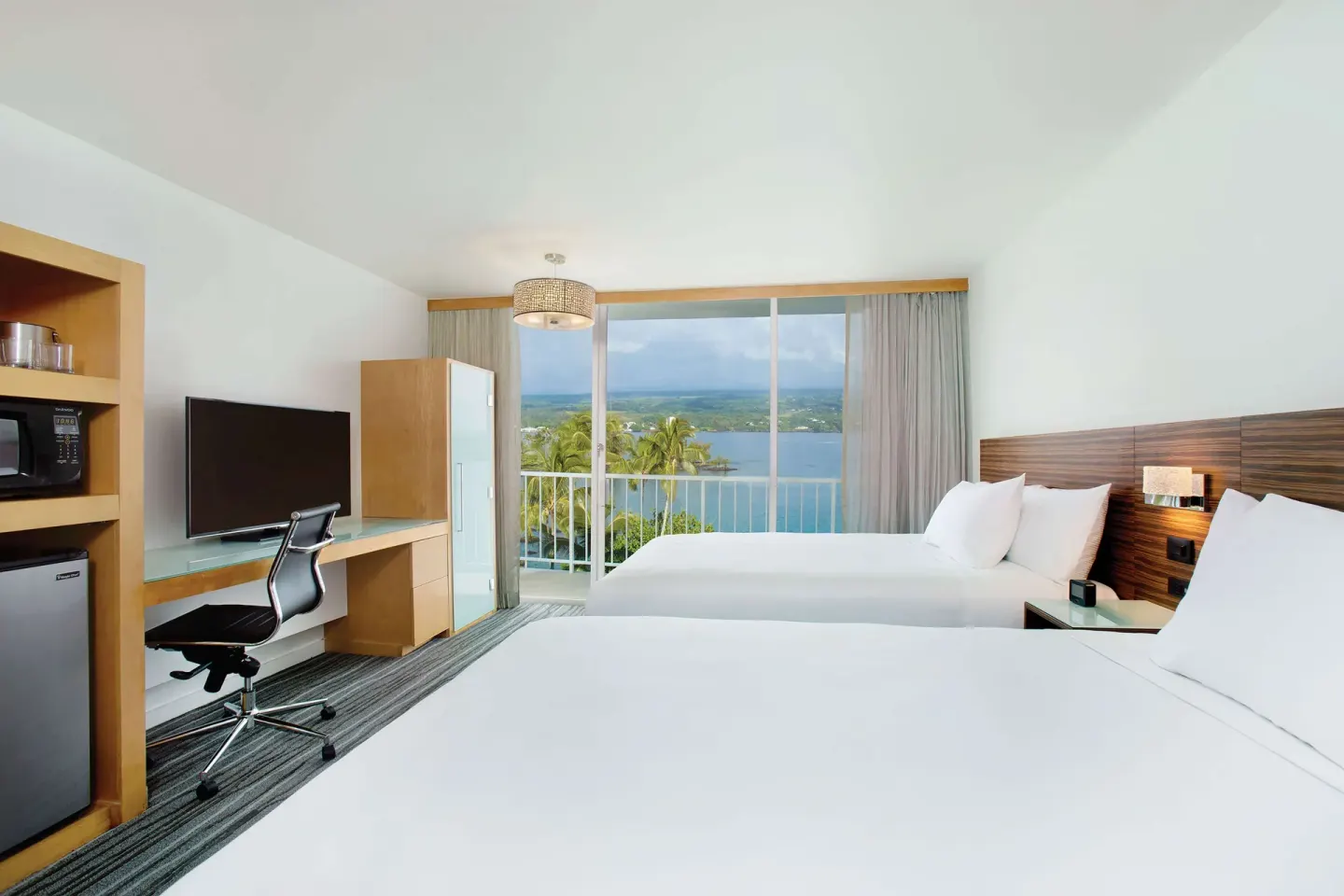 Oceanfront two-bed guest room with desk and lanai at Grand Naniloa Hotel Hilo.