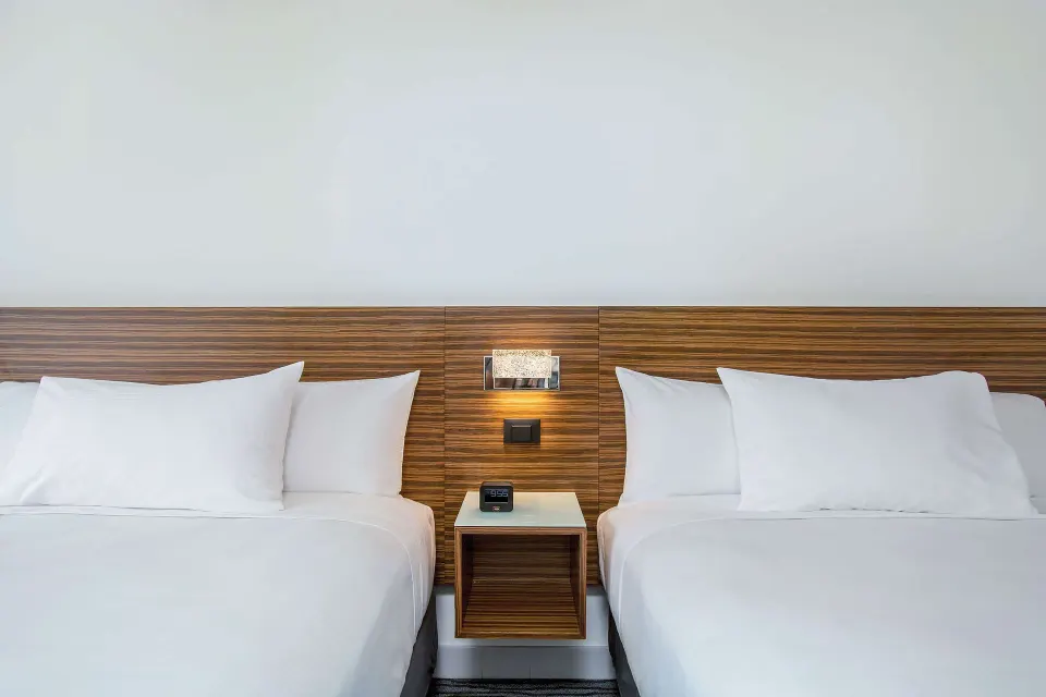 Two-bed guest room detail with wood headboard at Grand Naniloa Hotel Hilo.