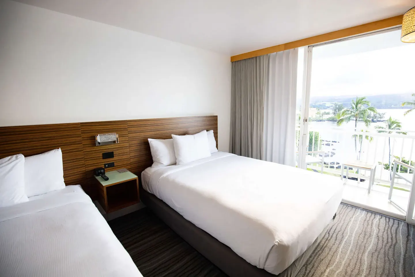 Oceanfront guest room with two beds and a bright lanai at Grand Naniloa Hotel Hilo.