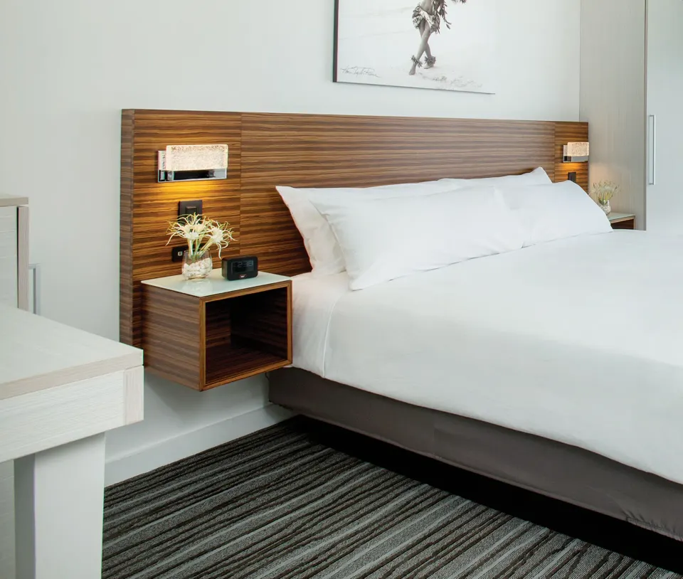 King bed with wood headboard and bedside lighting at Grand Naniloa Hotel Hilo.