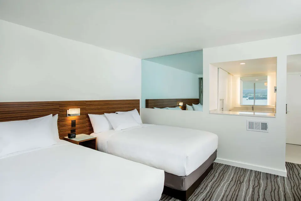 Two-bed guest room with vanity window and wall mirror at Grand Naniloa Hotel Hilo.