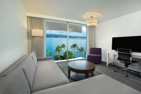 Suite living area with ocean-facing windows at Grand Naniloa Hotel Hilo.