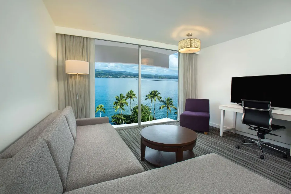 Suite living area with ocean-facing windows at Grand Naniloa Hotel Hilo.