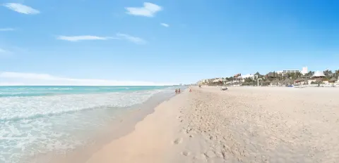 Long sandy shoreline with surf and resort palapas at Grand Oasis Cancun.