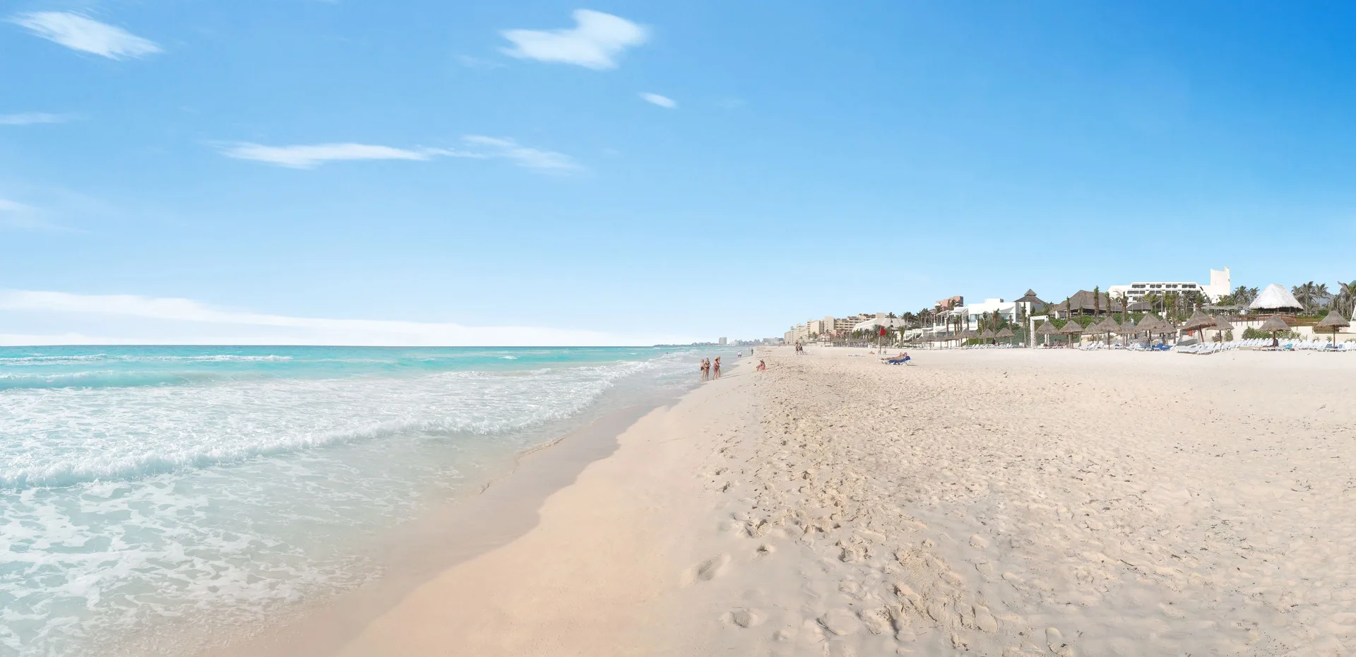 Long sandy shoreline with surf and resort palapas at Grand Oasis Cancun.
