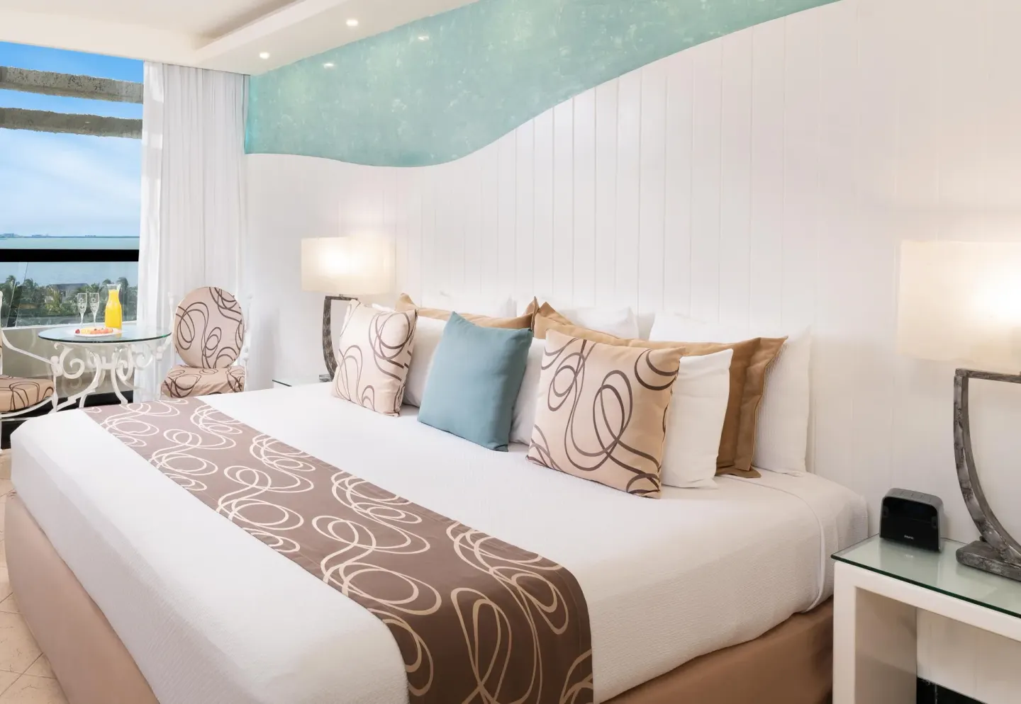 King bed with patterned pillows and a lagoon-view seating area at Grand Oasis Cancun.