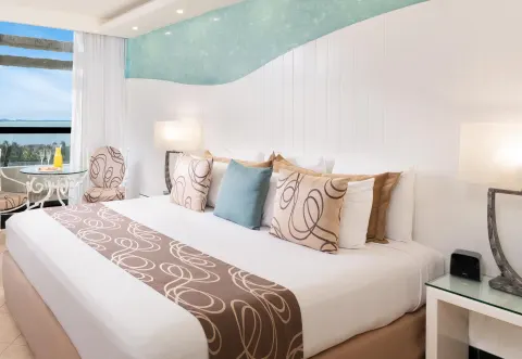 King bed with patterned pillows and a lagoon-view seating area at Grand Oasis Cancun.