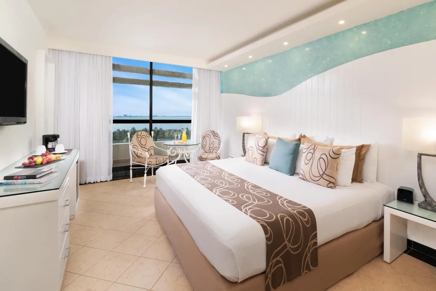 King-bed guest room with seating by a lagoon-view window at Grand Oasis Cancun.