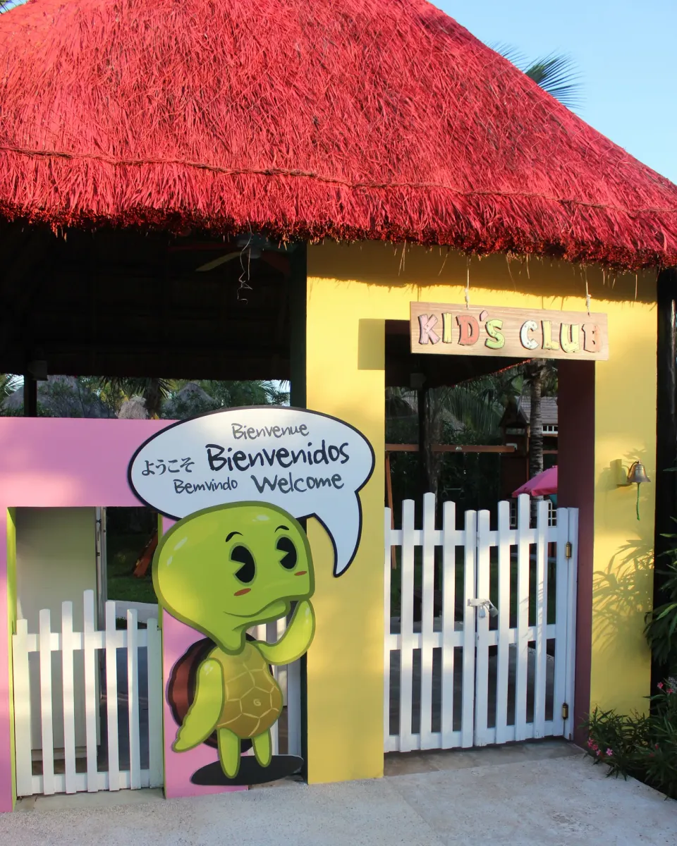 The kids club entrance has a white gate and colorful turtle sign at Grand Oasis Cancun.