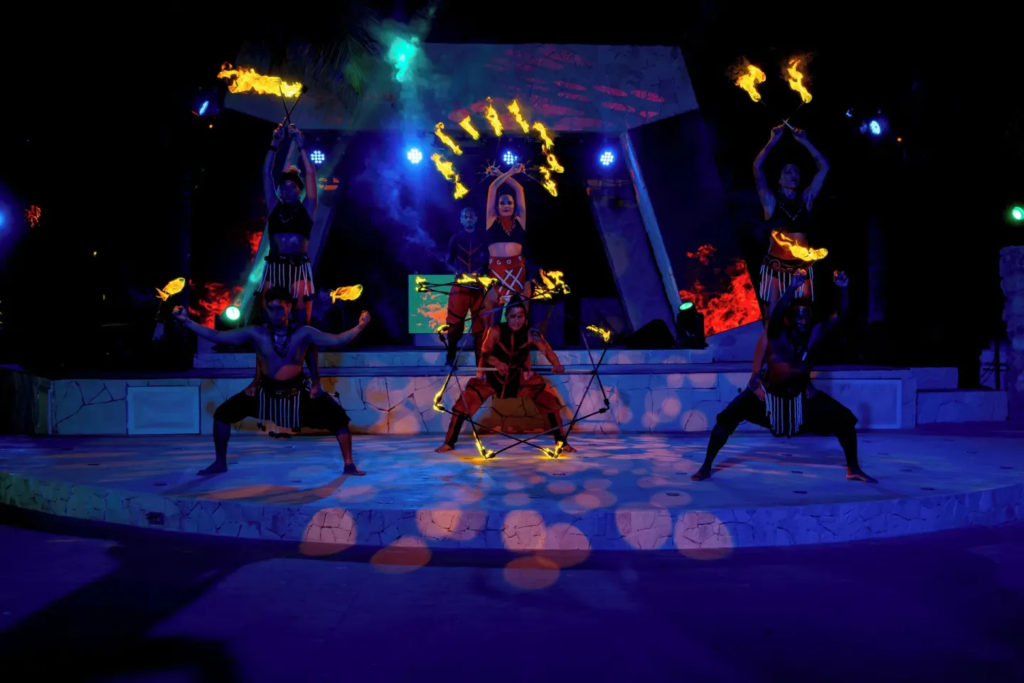 Fire dancers perform on an outdoor stage at night at Grand Oasis Cancun.