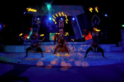 Fire dancers perform on an outdoor stage at night at Grand Oasis Cancun.
