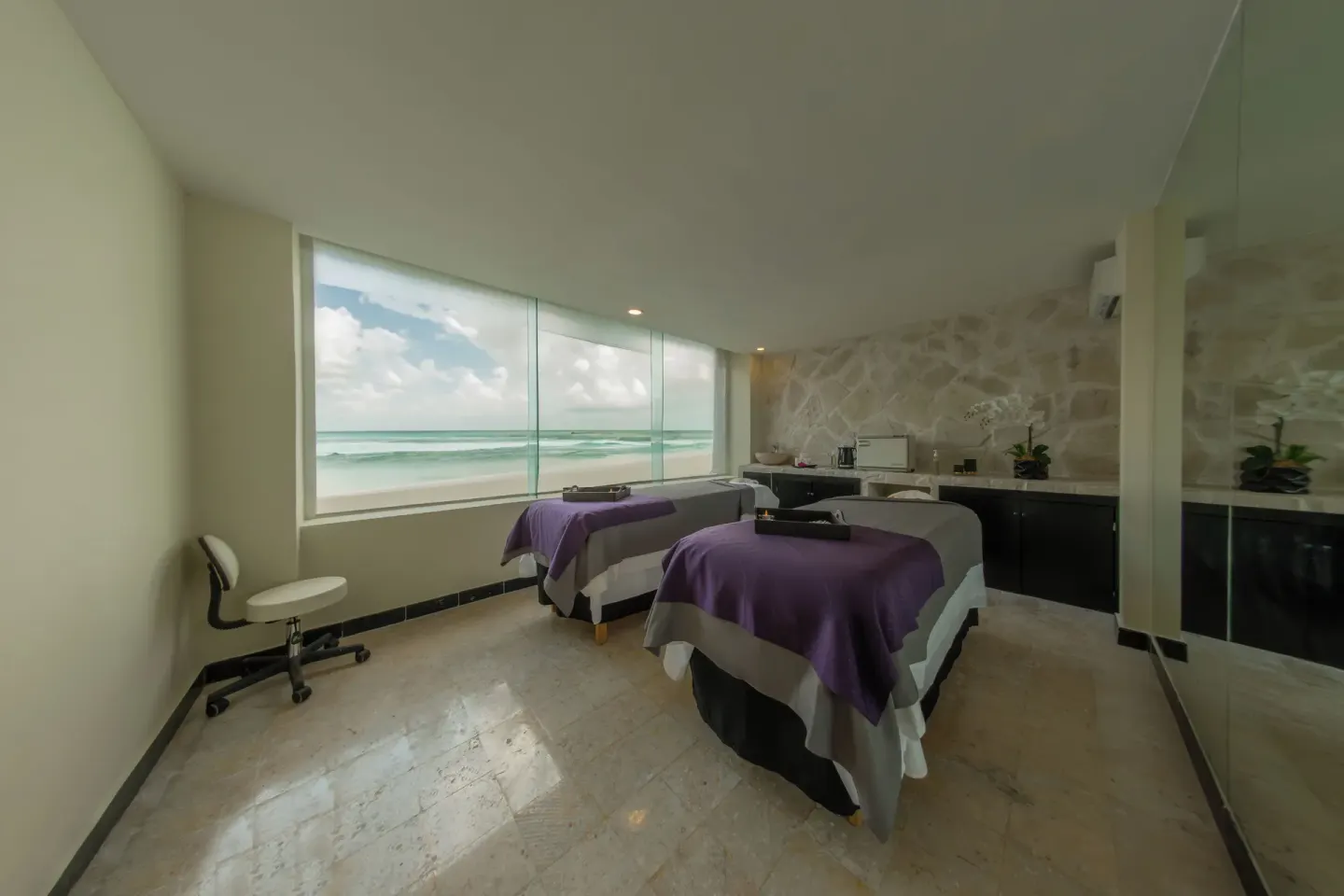 Spa treatment room with two massage tables and ocean view at Grand Oasis Cancun.