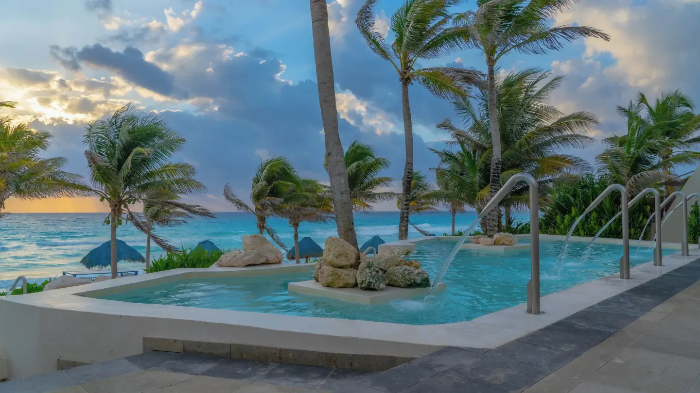 Oceanfront pool with waterfalls, rocks, and palms at Grand Oasis Cancun.