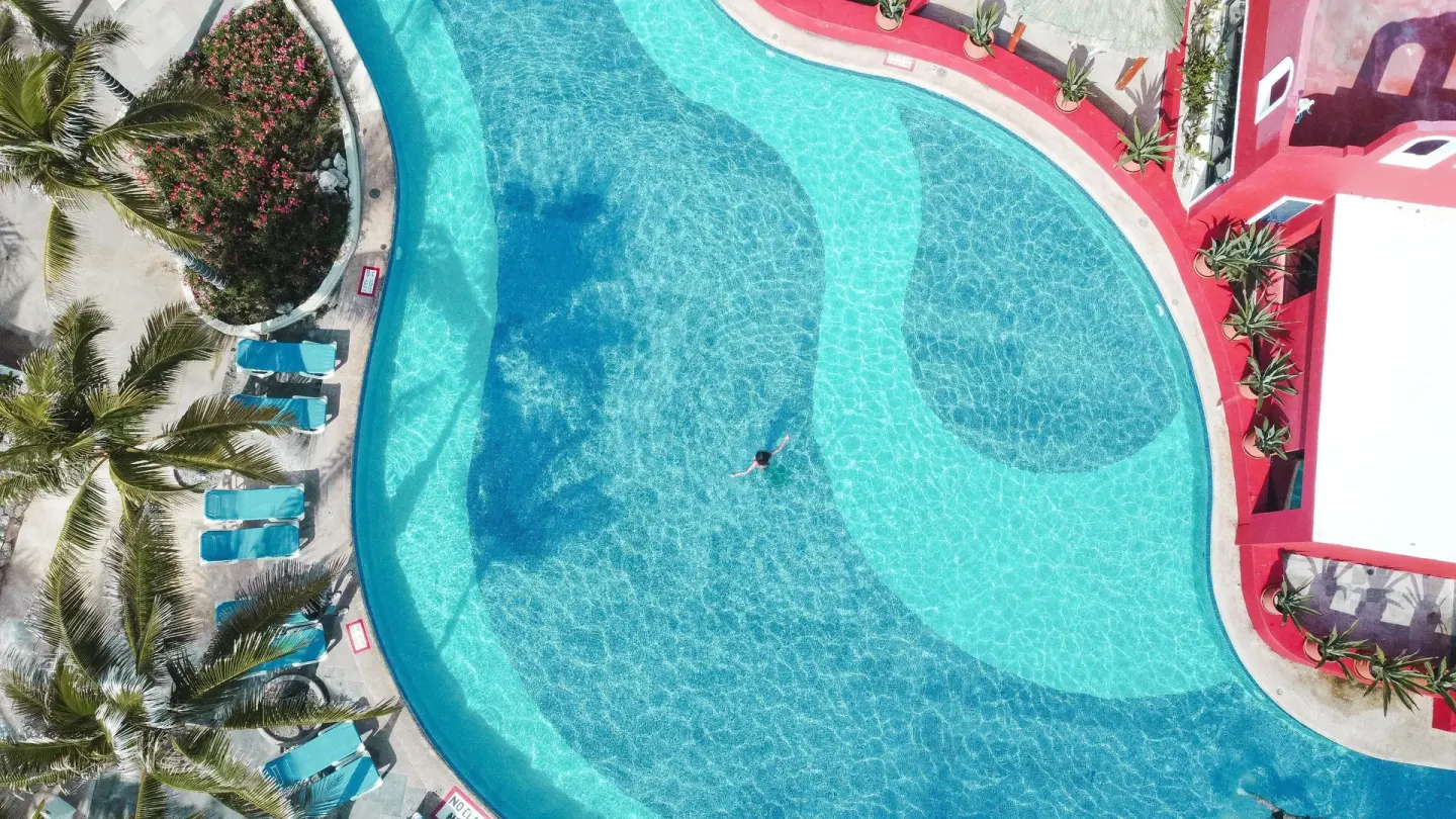 Overhead view of a curved turquoise pool with loungers at Grand Oasis Cancun.