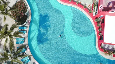 Overhead view of a curved turquoise pool with loungers at Grand Oasis Cancun.