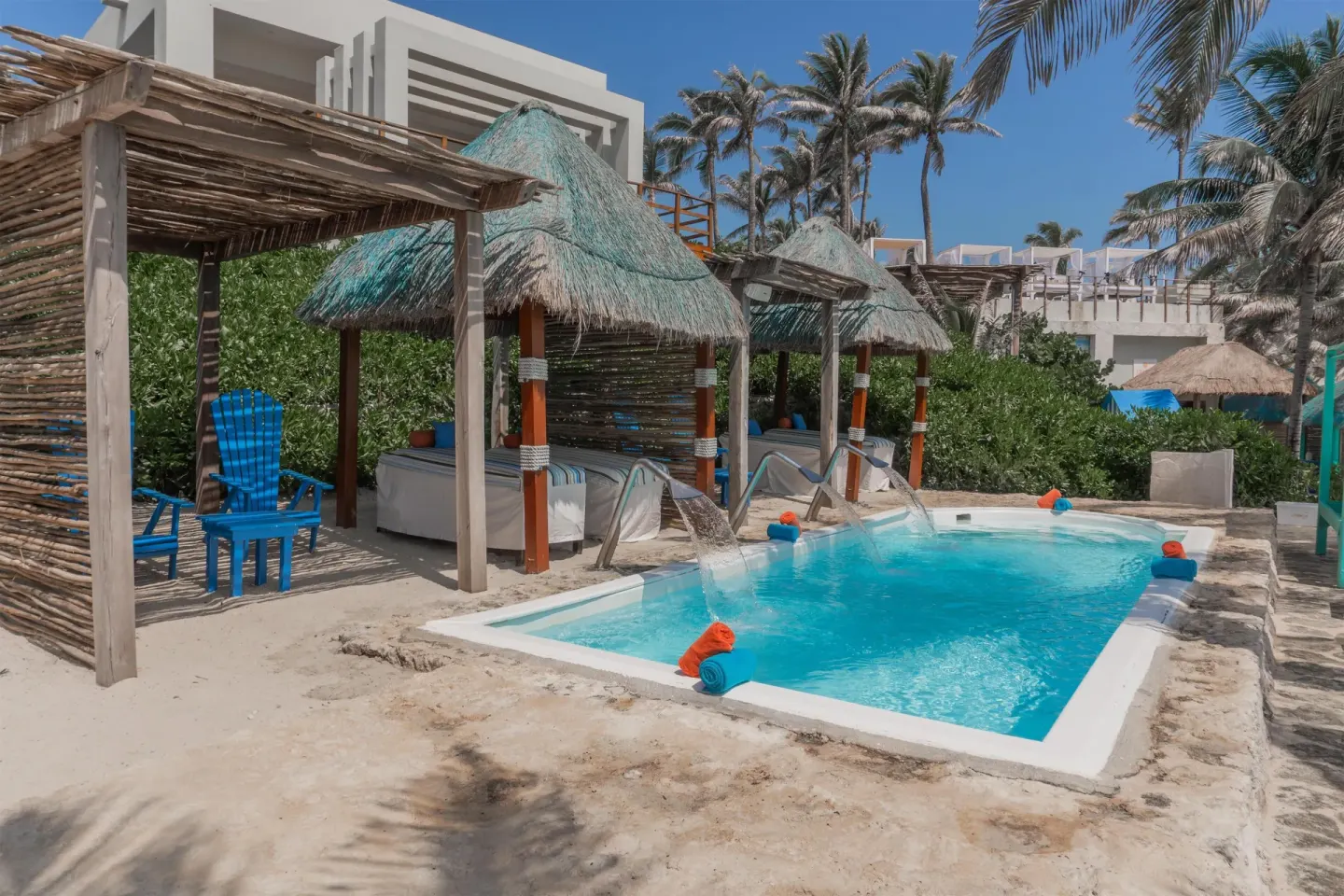 Thatched cabanas beside a small pool on the sand at Grand Oasis Cancun.